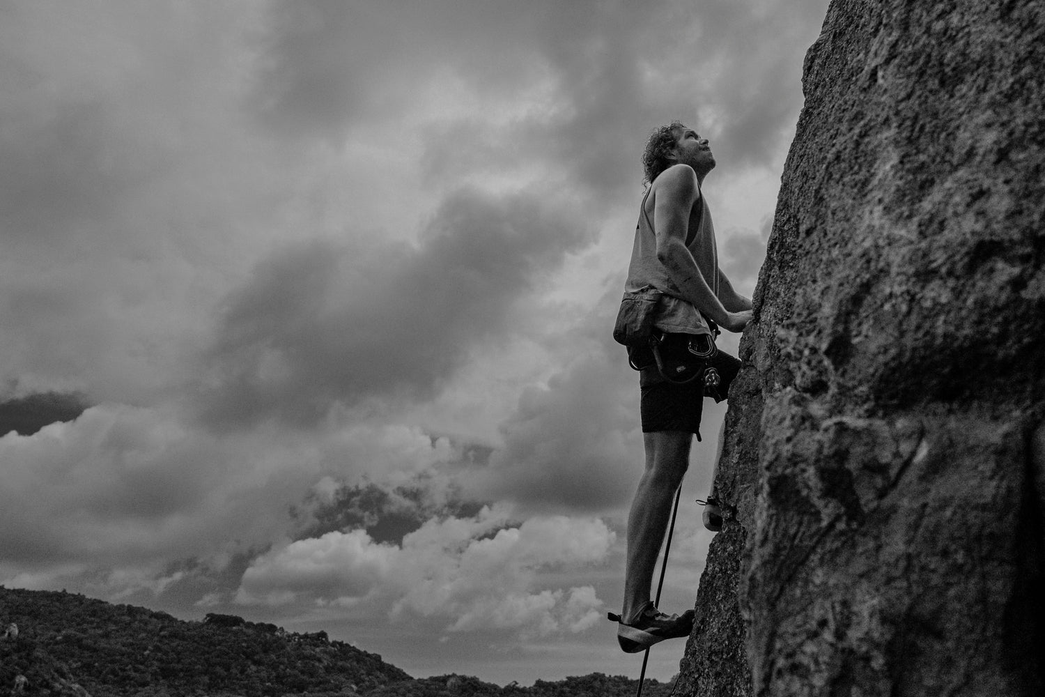 man climbs mountains, man is engaged in rock climbing, mountains, sport in the mountains, man on a rock climber Noah belay looks up, holds on to a rock.